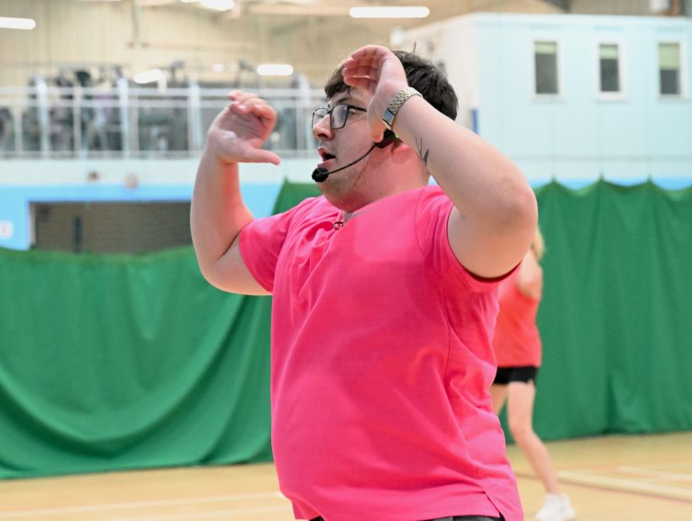 The Zumba instructor in a pink T-shirt leads the class in Cheadle
