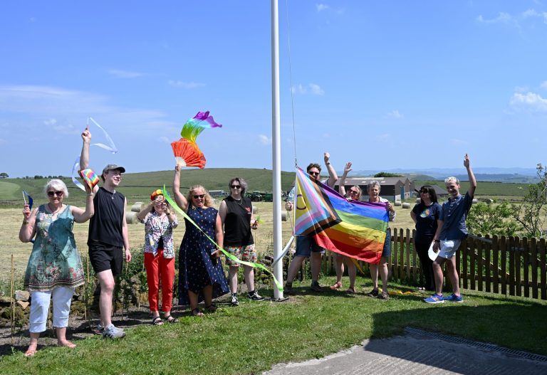 People wave rainbow streamers and flags on the moorland at Flash